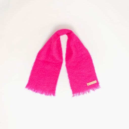 A bright pink scarf with fringed ends is laid out against a plain white background.