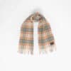 A plaid scarf with fringed ends is laid out against a plain white background.