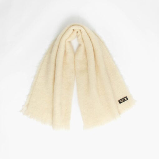 A cream fluffy wide scarf with fringed ends is laid out against a plain white background.