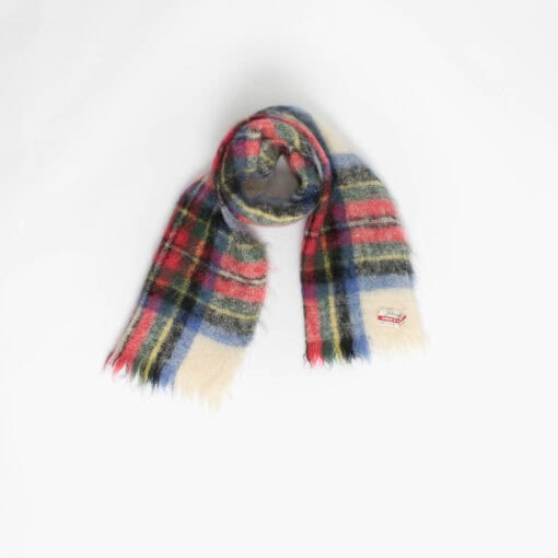 A plaid fluffy scarf with fringed ends is laid out against a plain white background.