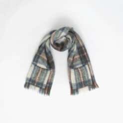 A pale plaid scarf with fringed ends is laid out against a plain white background.