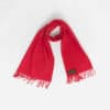 A red scarf with fringed ends is laid out against a plain white background